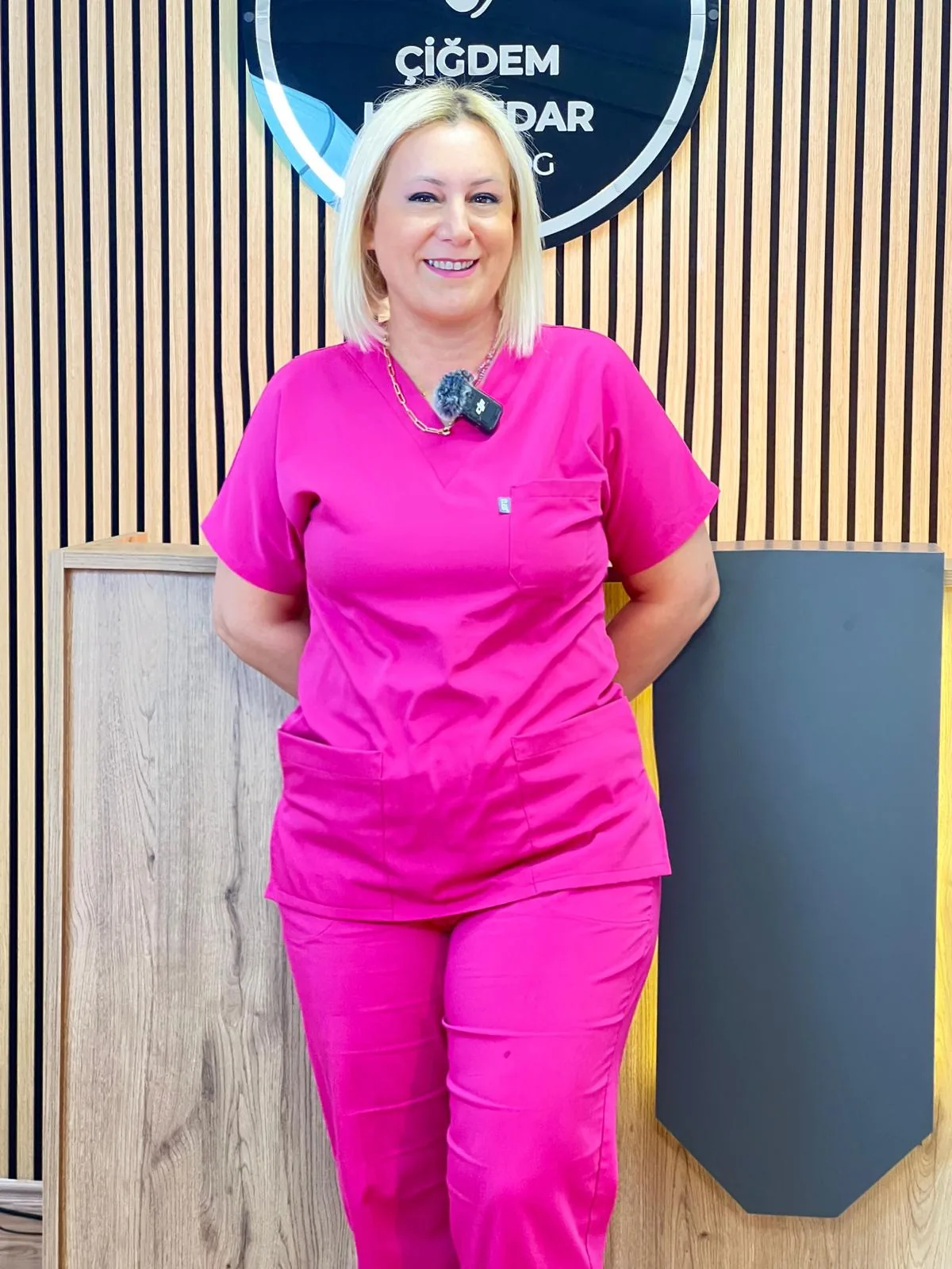 Podolog Çiğdem Haznedar Podolog Çiğdem Haznedar klinik logosu önünde portresi